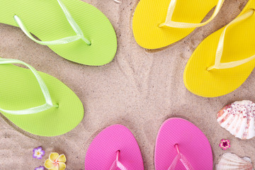 Bright flip-flops on sand, close up