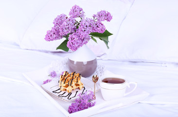 Wooden tray with light breakfast on bed