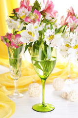 Freesias in glasses on table on fabric background