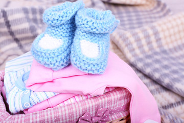 Baby clothes in basket on plaid in room