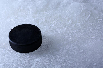 Black hockey puck on ice rink background
