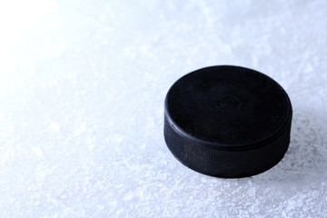 Black hockey puck on ice rink background