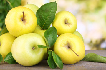 Ripe sweet apples with leaves on nature background