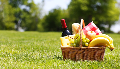 Picnic basket with food on green grass - 65299149