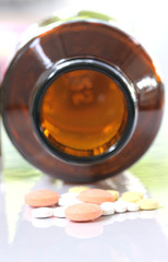 Many pills and pill bottle on white.