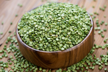 Wooden bowl with split dried green peas, horizontal shot