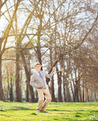 Senior man playing air guitar in the park