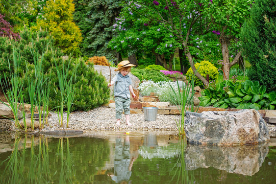 Cute little boy fishing by the pond in the beautiful garden