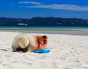 Fototapeta na wymiar hat, bag, sun glasses and flip flops on the beach