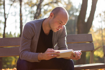 Young man relaxing in a park, reading a book
