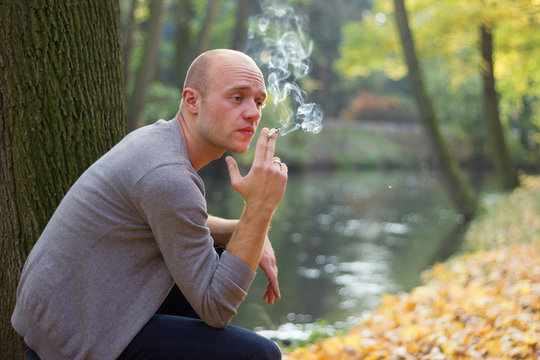 Young man relaxing in a park, smoking a cigarette