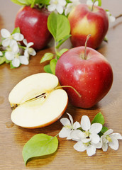 Red ripe apple fruits and apple flower on the wooden table