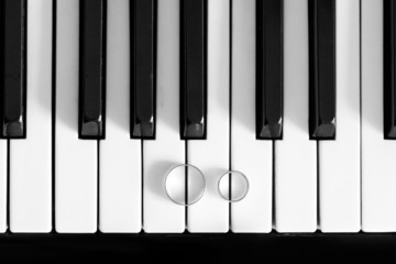 Naklejka premium wedding rings on piano black and white closeup
