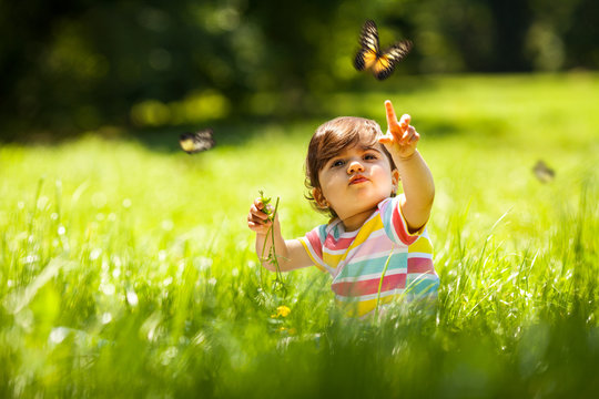 Baby girl playing with butterfly.