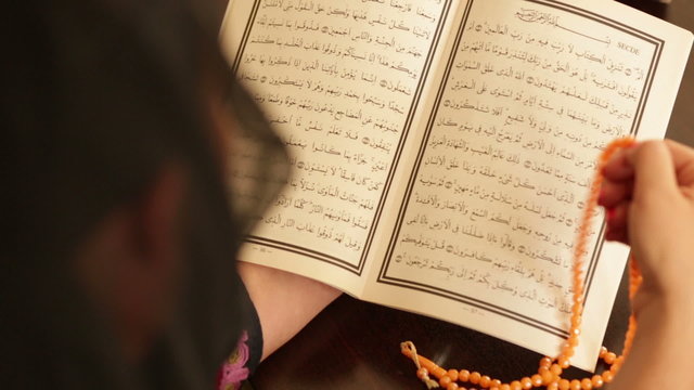 Muslim woman praying and reading koran