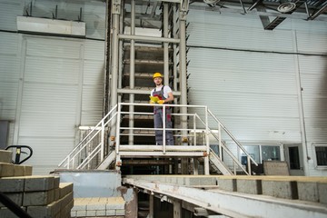 Man in a safety hat taking notes on a factory