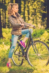 Fototapeta na wymiar Cheerful teenage girl listens music on a bicycle outdoors
