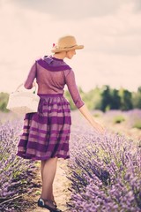 Woman in purple dress and hat with basket in lavender field