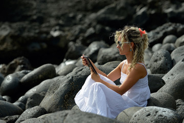 Fototapeta na wymiar young woman using tablet on rocky beach