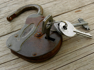 old padlock with keys on wooden background
