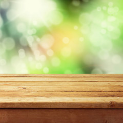 Empty wooden deck table with foliage bokeh background.