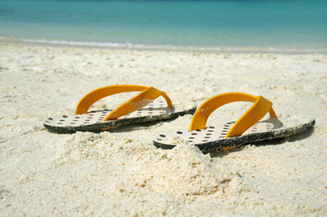 Obraz premium Summer vacation background with a pair of sandals on beach