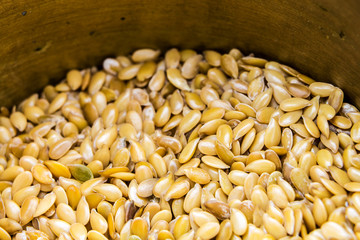 Golden flax seeds inside bronze mortar closeup