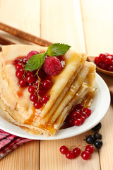 Delicious pancakes with berries, jam and honey on wooden table