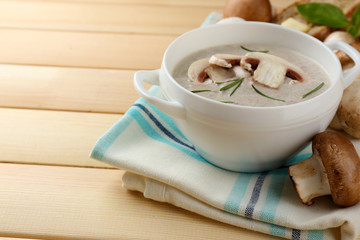 Mushroom soup in pot, on color napkin,  on wooden background