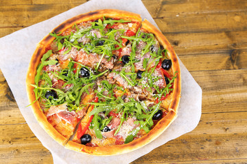 Pizza with arugula on color wooden background