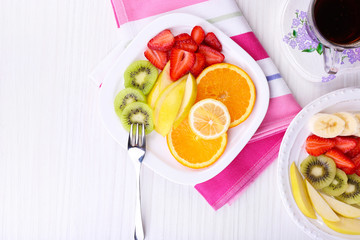 Various sliced fruits on plates on table close-up