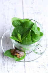 Mint leaves in glass cup on color wooden background