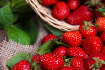 Ripe sweet strawberries in wicker basket and mint leaves