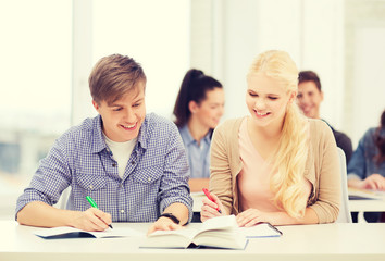 two teenagers with notebooks and book at school