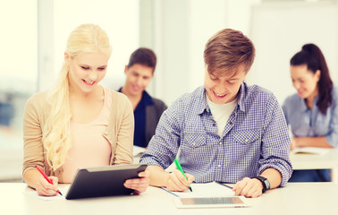 Fototapeta premium two smiling students with tablet pc and notebooks