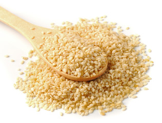 Wooden spoon with sesame seeds on a white background
