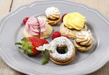 Assorted cookies and fruits on grey ceramic plate