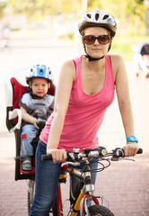 Caucasian young woman on a bicycle with little son behind