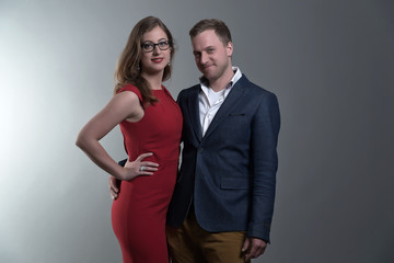 Fashion couple wearing a red dress and blue jacket. She is weari