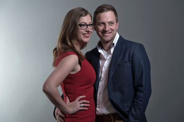 Fashion couple wearing a red dress and blue jacket. She is weari