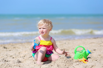 Cute little girl building sand castles on tropical beach