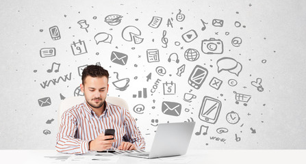 Young businessman with all kind of hand-drawn media icons in bac