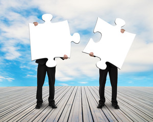 two men holding puzzles on wooden floor