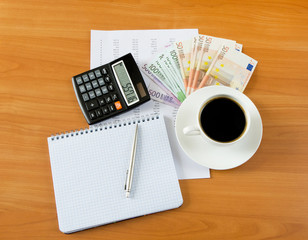 Office supplies with money and cup of coffee close up