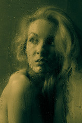 Portrait of naked girl behind the wet glass