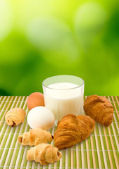 image of a glass of milk, eggs and cookies on a green background