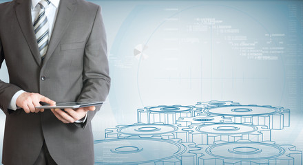 Businessman hold tablet pc. Gears and graphs