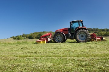 Red tractor mowing the meadow, Czech Republic