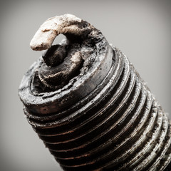 Auto service. Old spark plug as spare part of car.