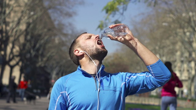 Jogger drinking water in park, slow motion shot at 60fps, steady